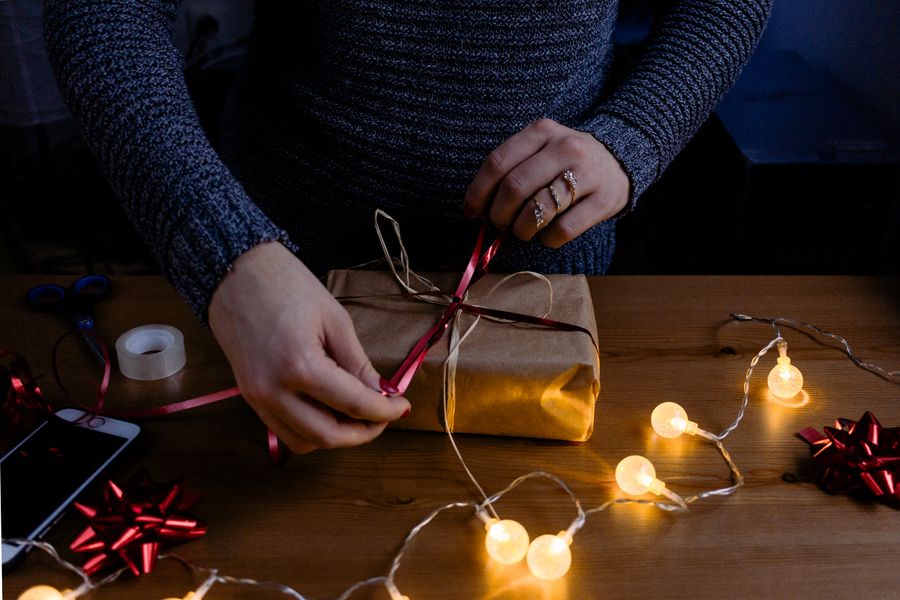 Hands adding ribbon to a carefully wrapped gift