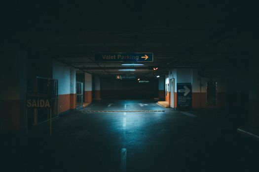 A dark underground parking garage with valet parking signage.