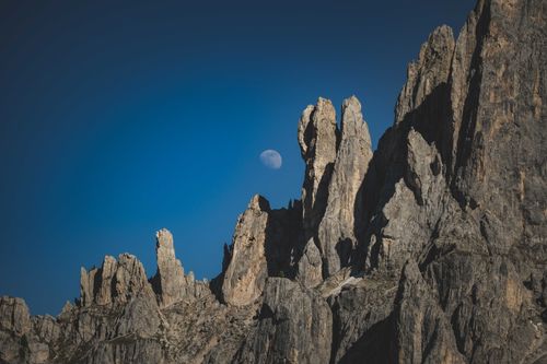 Free Breathtaking view of rugged mountain peaks against a clear sky, with the moon visible in daylight. Stock Photo