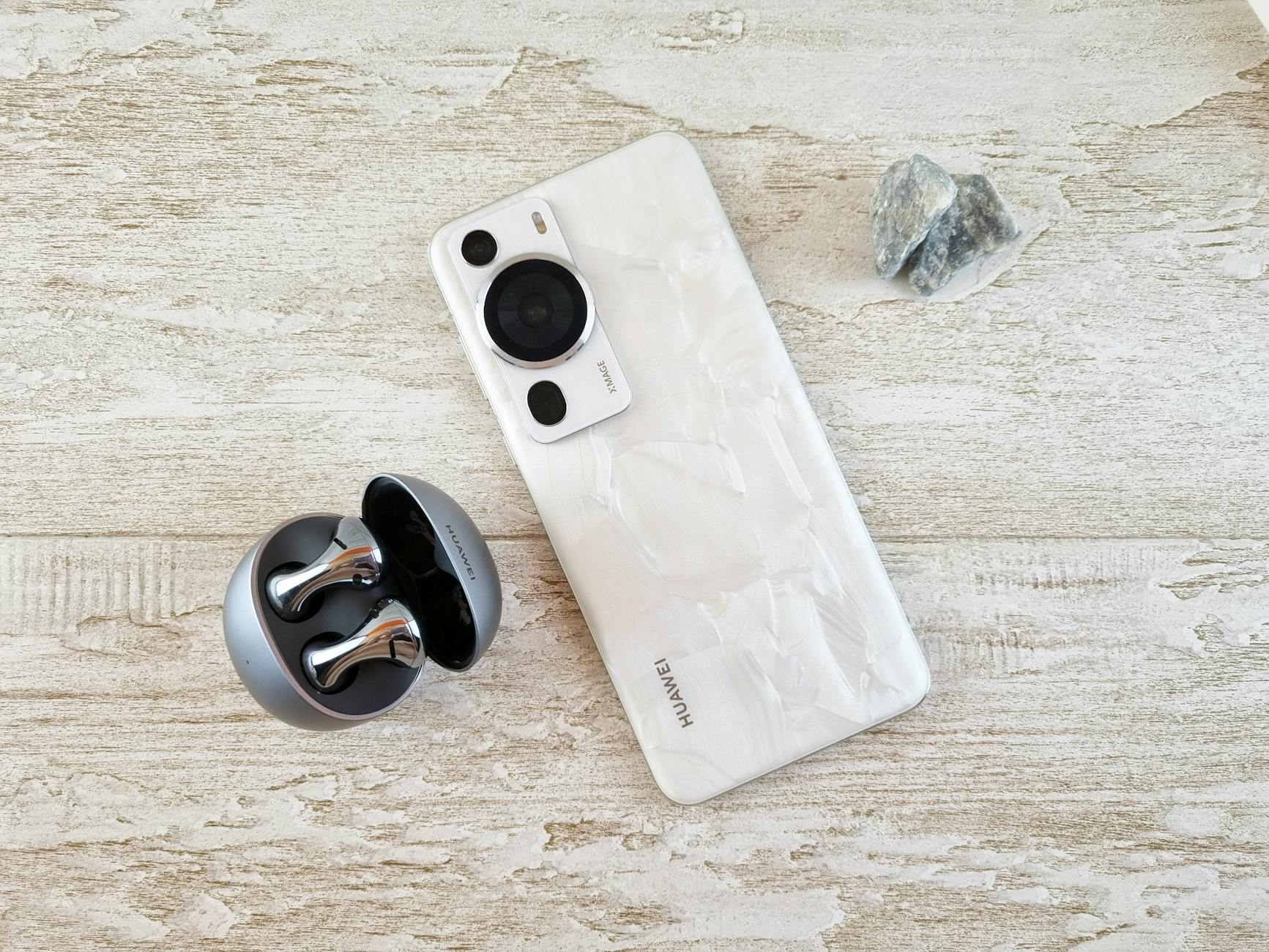 A stylish white smartphone and wireless earbuds on a textured surface for tech enthusiasts.