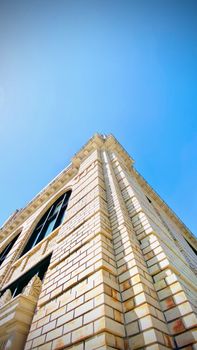 Low angle shot of a brick building facade against a clear blue sky, emphasizing architectural elegance.