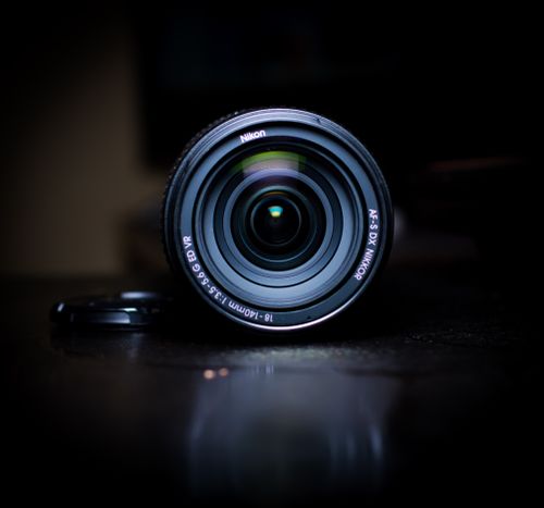 Free Detailed view of a camera lens on a black table. Ideal for technology and photography themes. Stock Photo