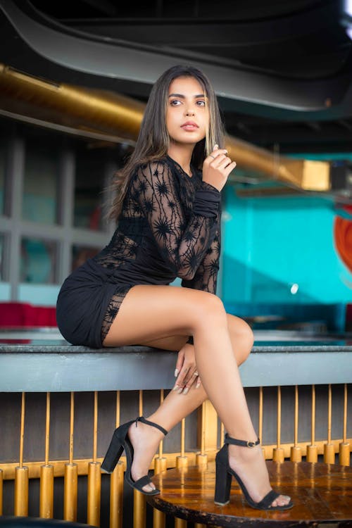 Model Sitting in Black Clothes and High Heels
