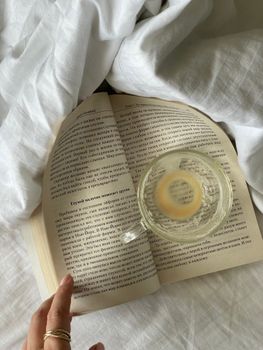Cozy scene of an open book with a half-empty coffee cup on white bedding, offering a serene morning vibe.