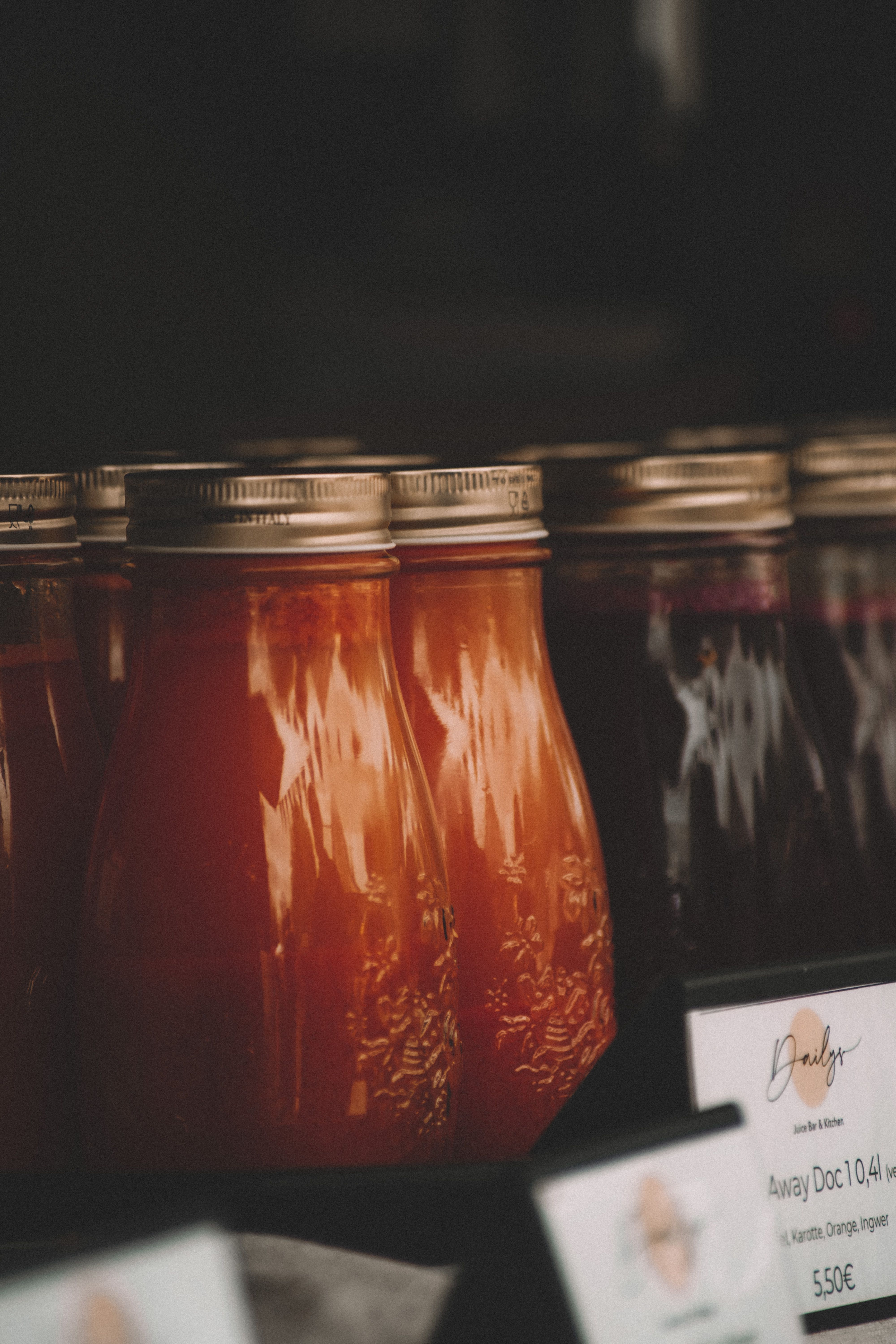 Close-up of various bottled juices with rustic caps on display at a local market.