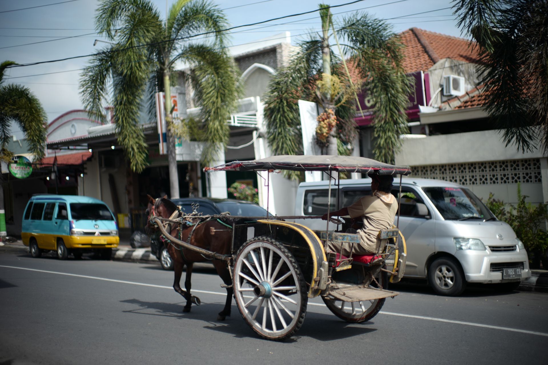 A classic horse-drawn carriage travels down a Jakarta street, showcasing traditional transport amidst modern city life.