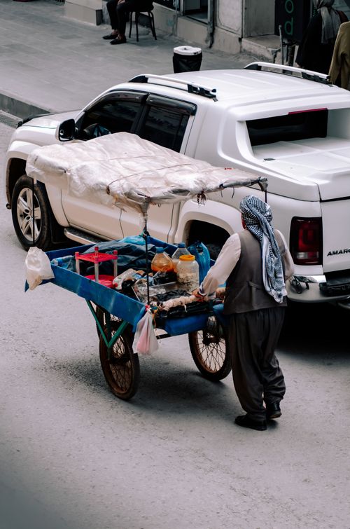 Free Aerial view of a street vendor pushing a cart beside a parked vehicle in Silopi, Şırnak. Stock Photo