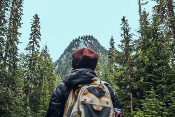 Hiker with a pack facing a forested mountain ridge — photo by Chris G on Pexels