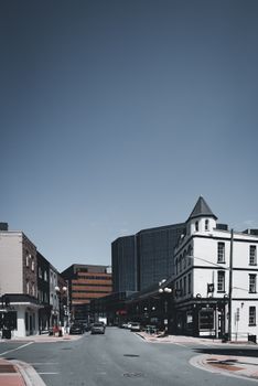 A vertical shot of a city street showcasing historic and modern architecture under a clear sky.