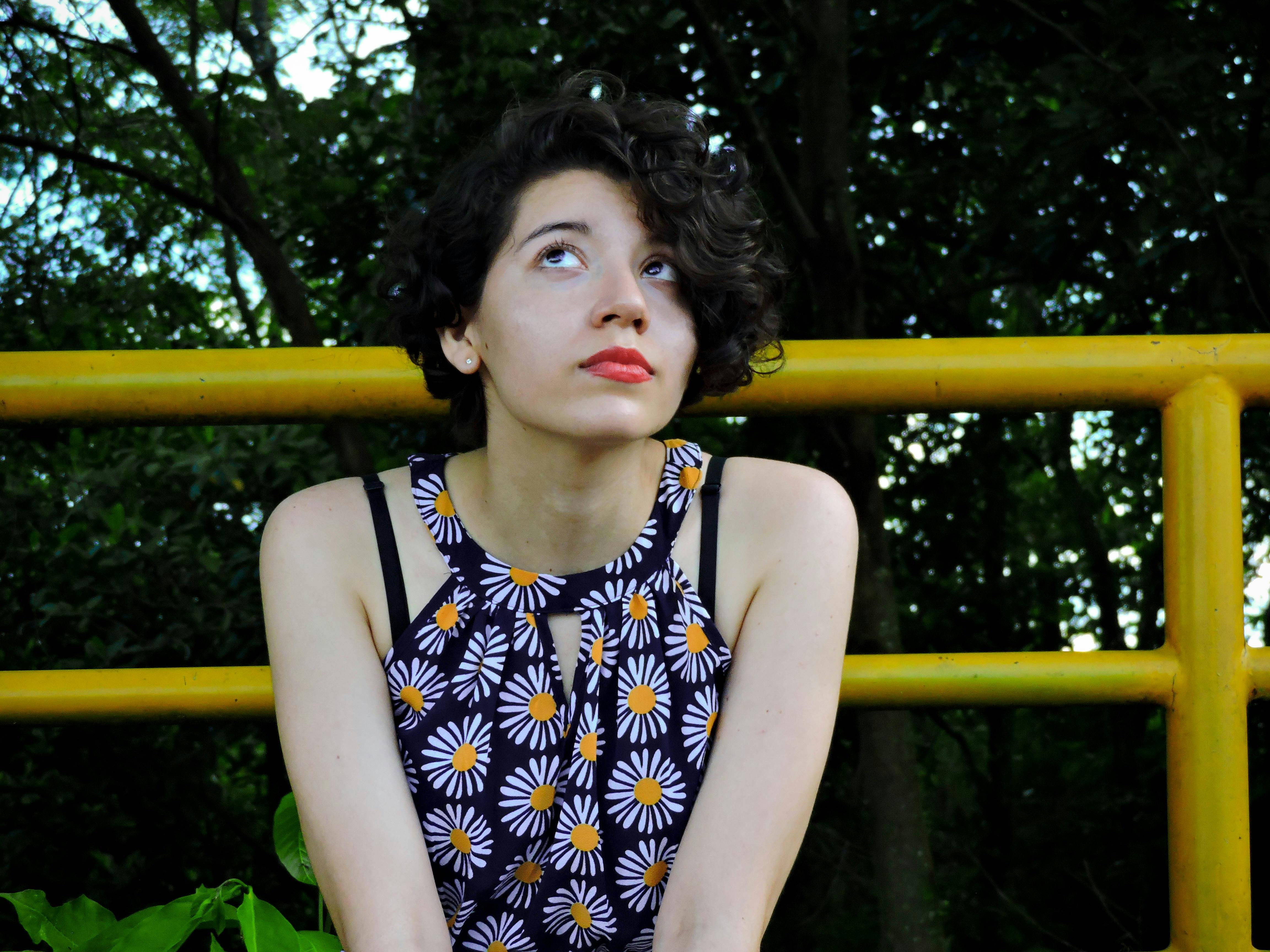 穿着雏菊图案衣服的年轻女子若有所思地反对着某种性质