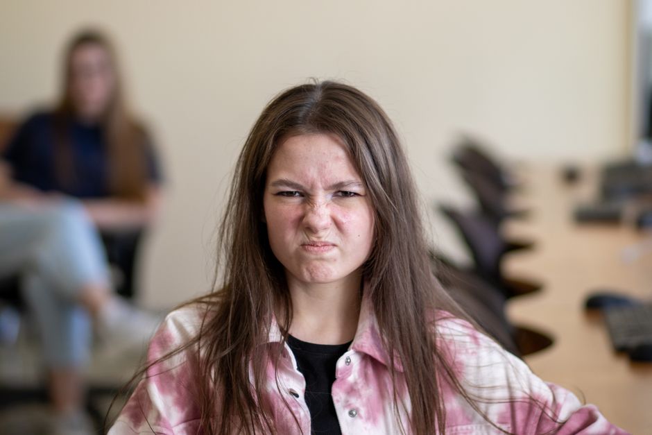 Why does my essay sound like AI when I wrote it myself? 3 An angry teenage girl sitting in a classroom, displaying a frustrated expression.