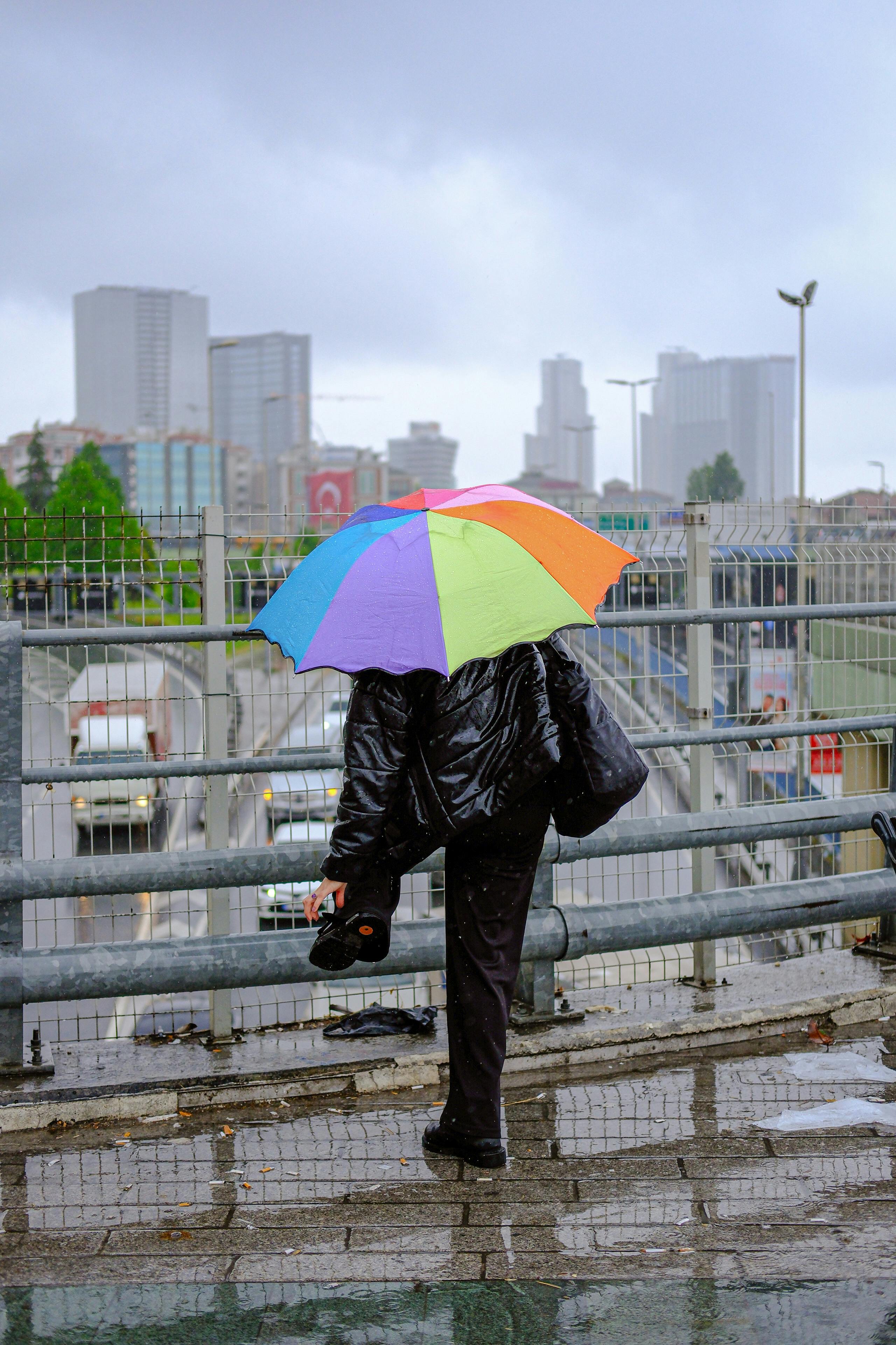 a person with an umbrella standing on a bridge