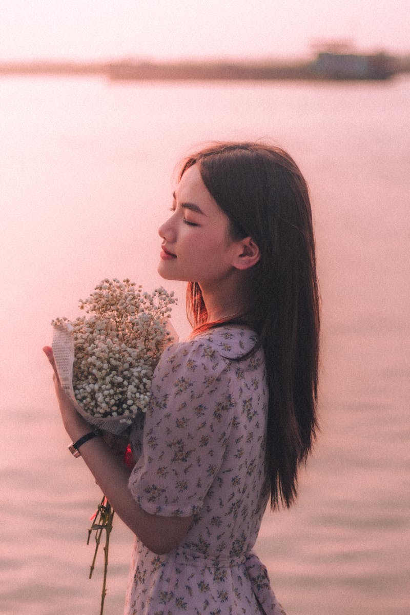 Young woman in a dress holding a bouquet by the water