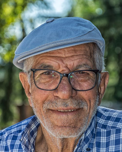 Portrait of an Old Smiling Man in Eyeglasses and Cap