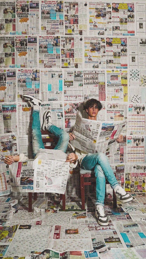 Men Sitting and Holding Newspapers in a Room with Newspapers on the Walls 