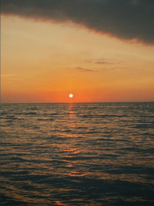 Free A captivating sunset scene with a dramatic sky over a calm ocean horizon. Stock Photo