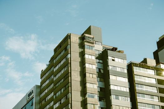 Low angle view of a modern urban residential building with clear blue skies, highlighting architectural design.