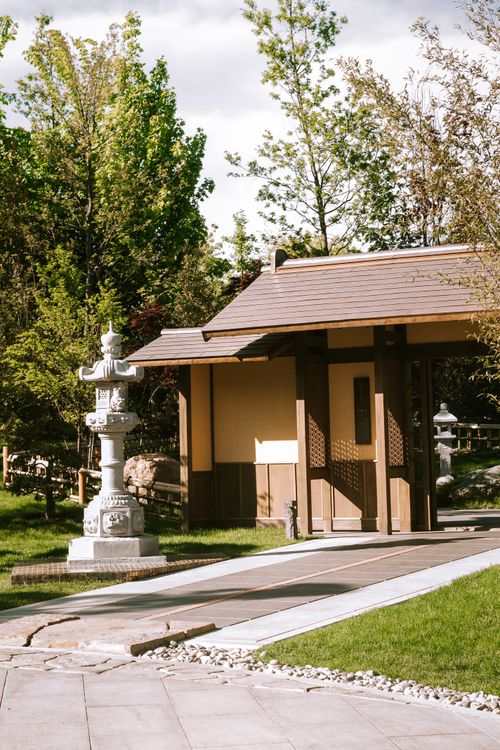 Free Tranquil Japanese garden featuring traditional gate and stone lantern under clear skies. Stock Photo