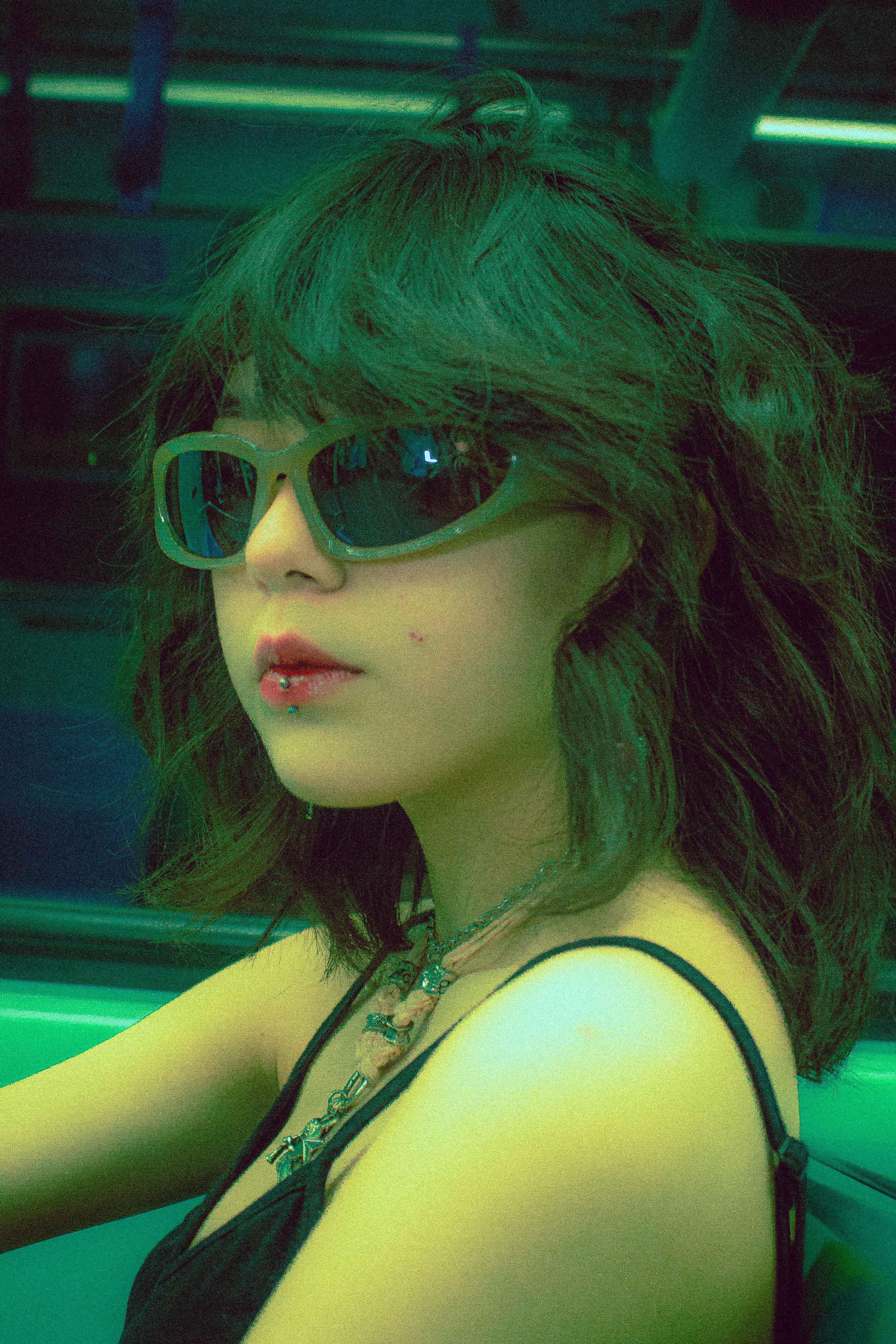 Stylish woman with sunglasses and lip piercing in a subway setting, exuding coolness.