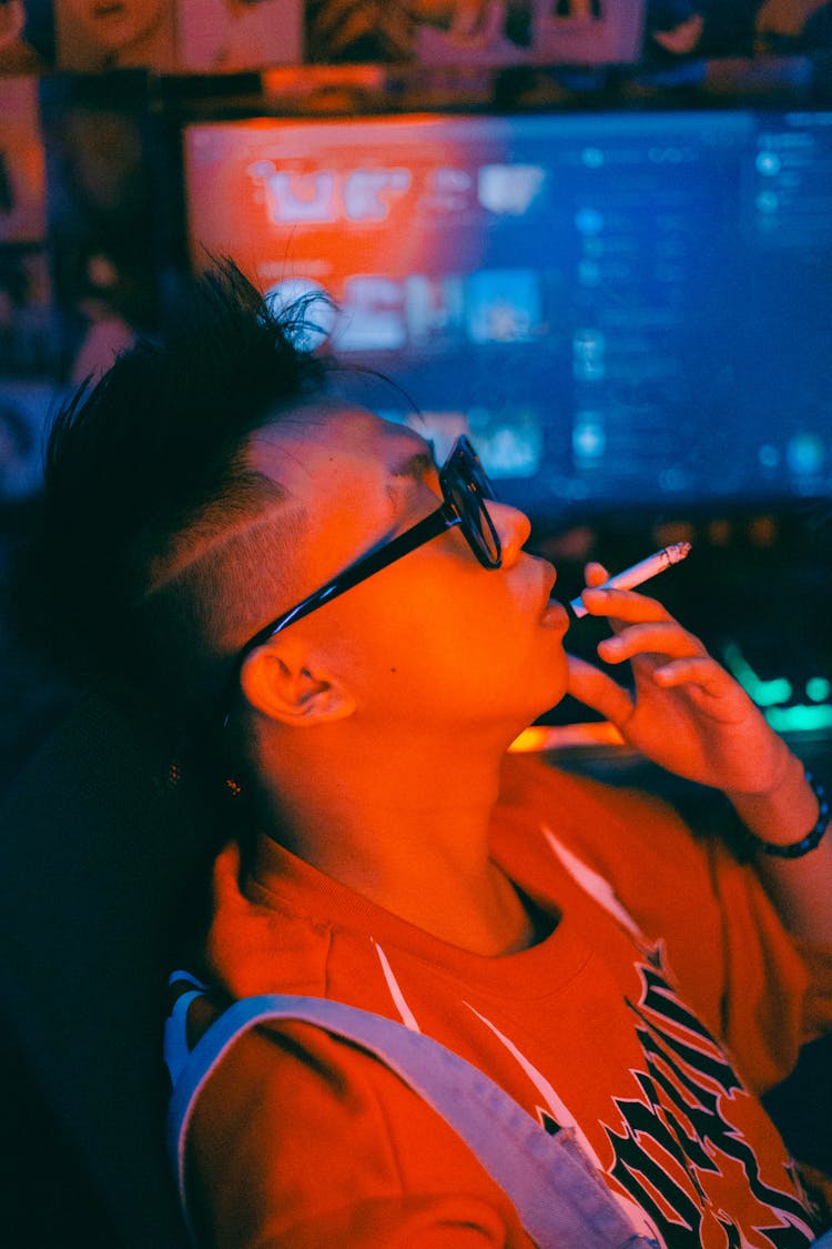 Young Man Sitting In Front Of A Computer And Smoking A Cigarette 