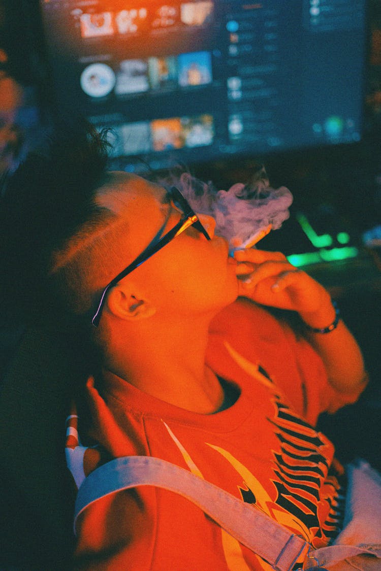 Young Man Sitting In Front Of A Computer And Smoking A Cigarette 