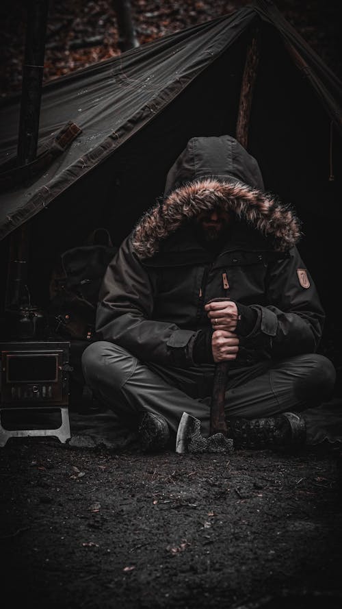 Man Sitting by Tent with Axe