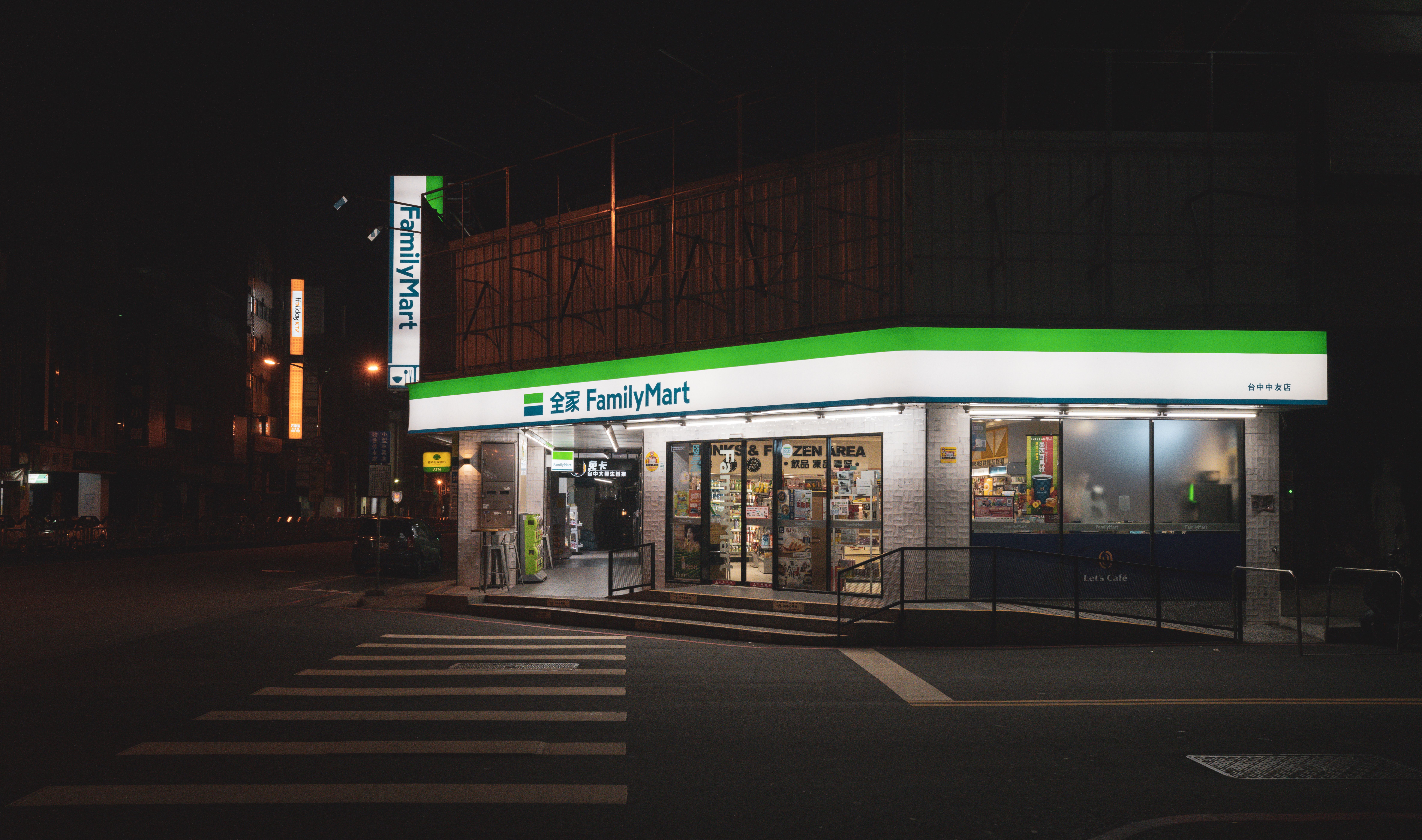 Illuminated FamilyMart store facade on city street at night.