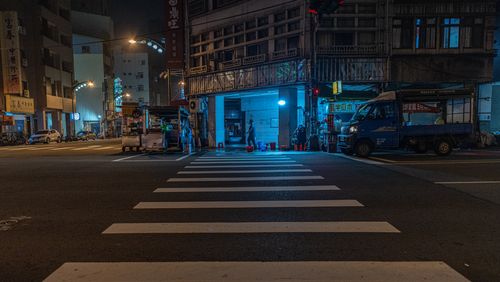 Free A vibrant city night scene featuring a zebra crossing and street vendors under ambient lighting. Stock Photo
