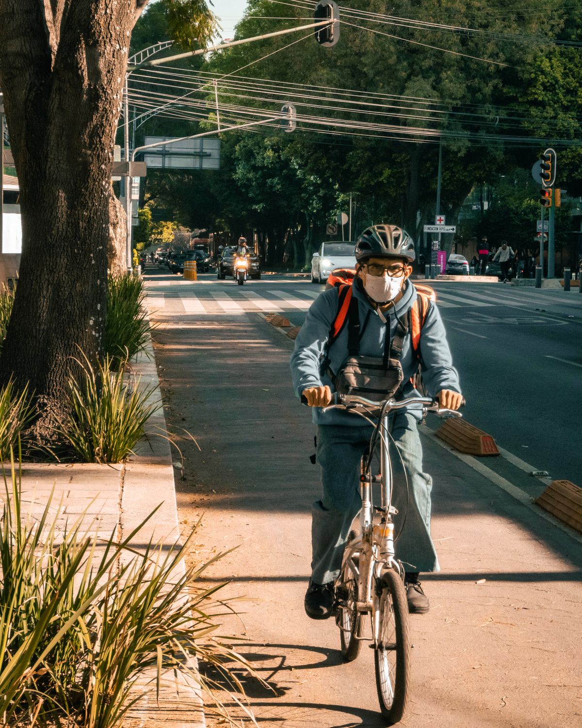 Helmeted cyclist riding through a lively urban street