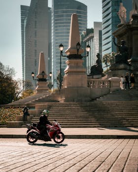 Motorcyclist rides past the Angel of Independence in vibrant Mexico City street scene.