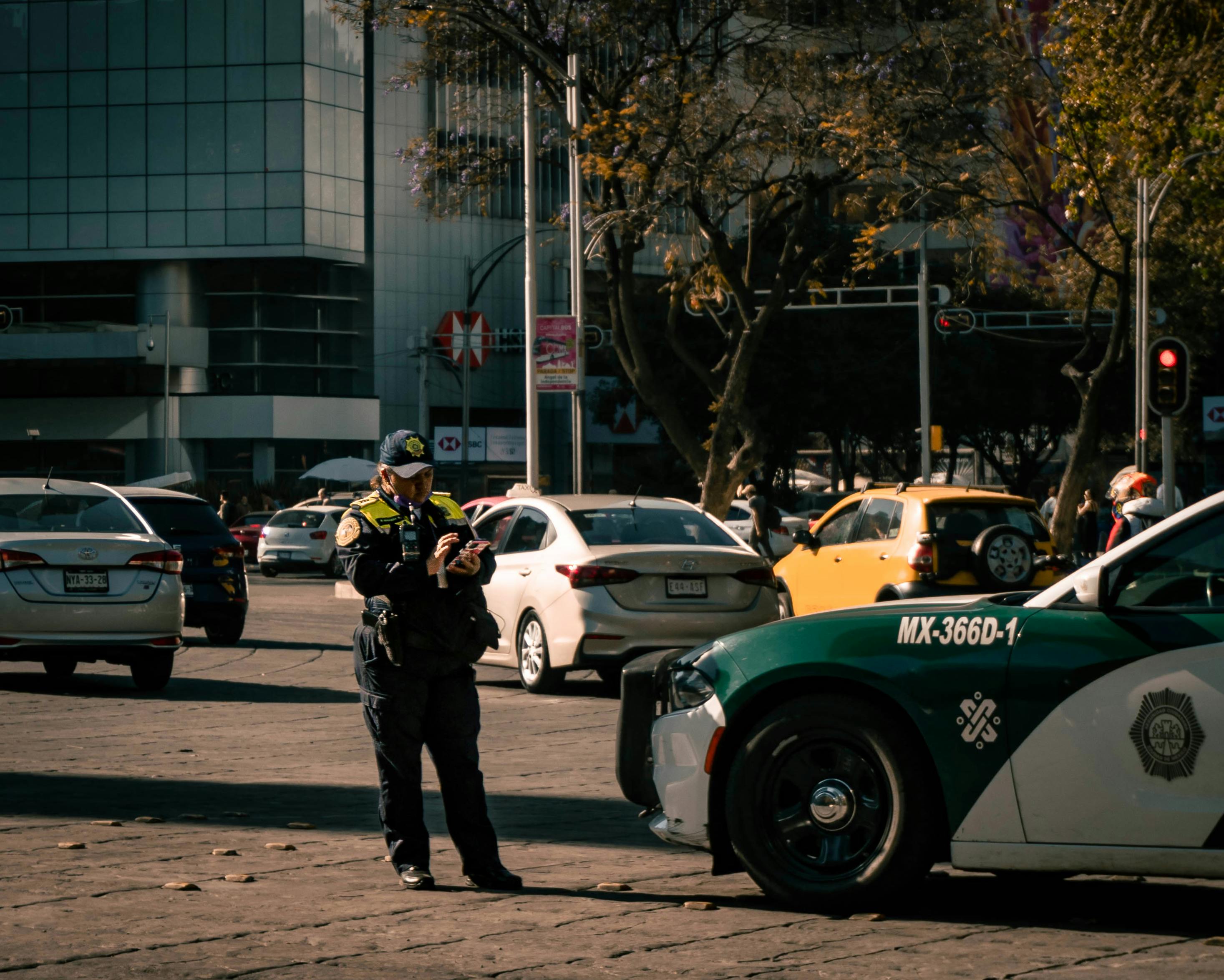 Policewoman in uniform ticketing a car in urban Mexico City setting.