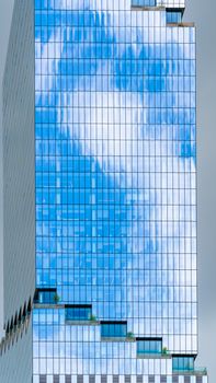 Skyscraper in New York City reflecting blue sky and clouds, showcasing modern architecture.