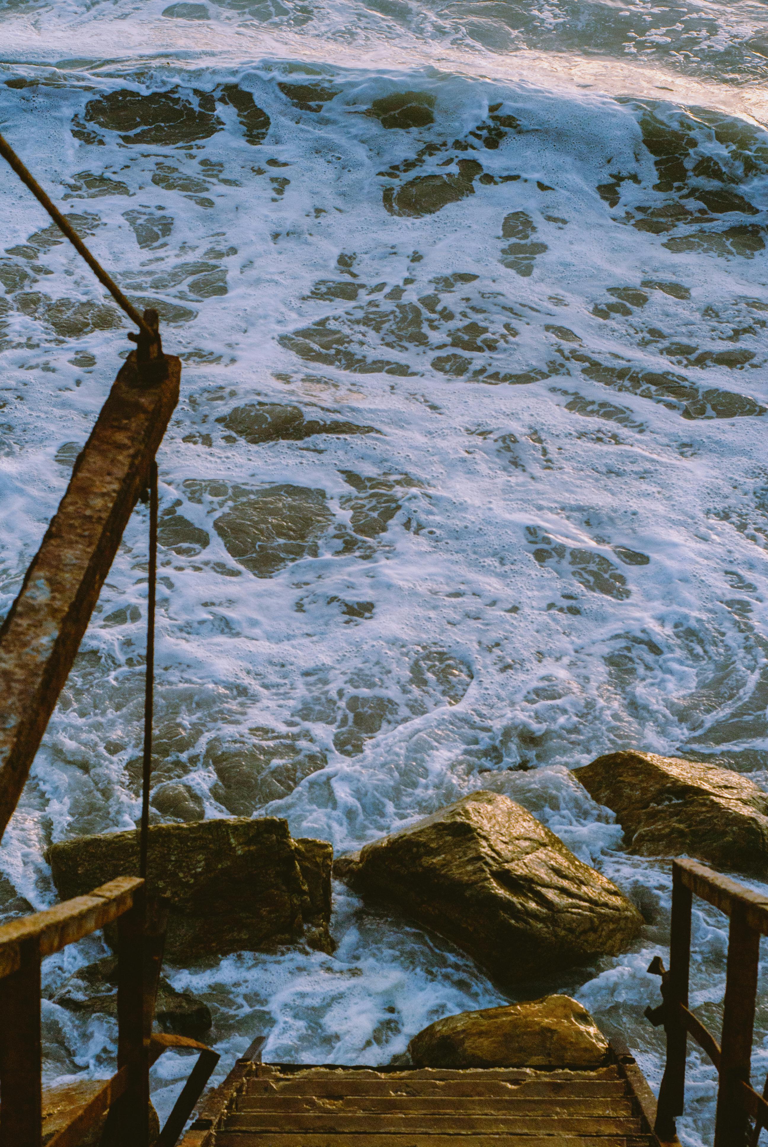 Rustic steps leading to foamy ocean waves crashing on rocks in Tijuana, Mexico.