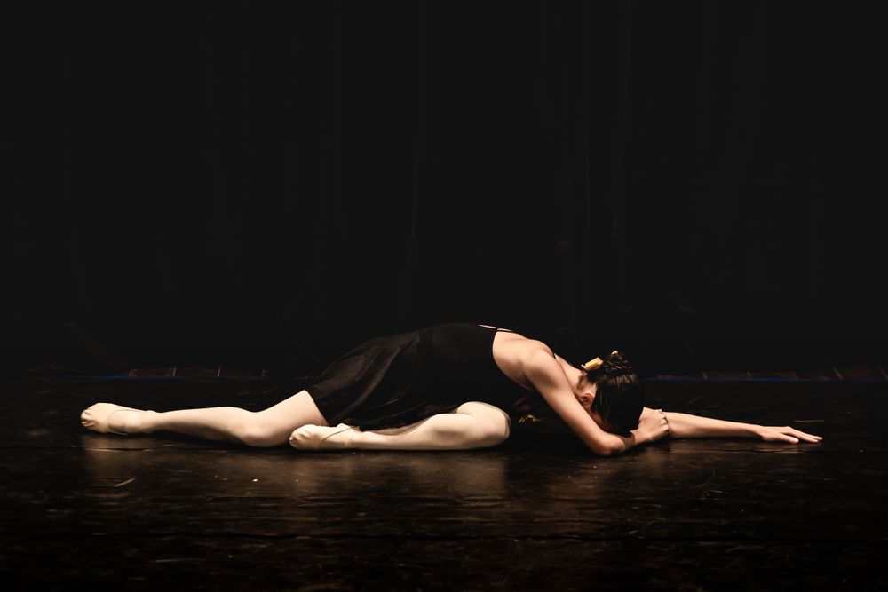 Dancer resting low on a darkened studio floor — photo by alexandre saraiva carniato on Pexels