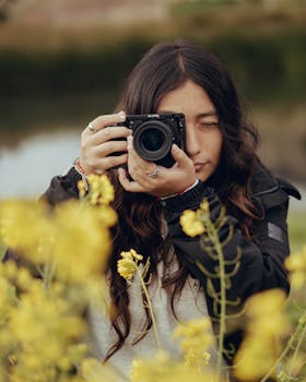 A woman with long hair capturing photos amidst vibrant flowers in Huaraz, Peru.