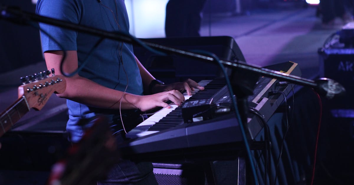 A musician performs on a keyboard during a dynamic live concert, surrounded by instruments.