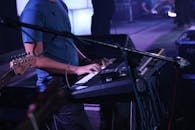 在充满活力的现场音乐会上，一位音乐家用键盘表演，周围摆满了乐器