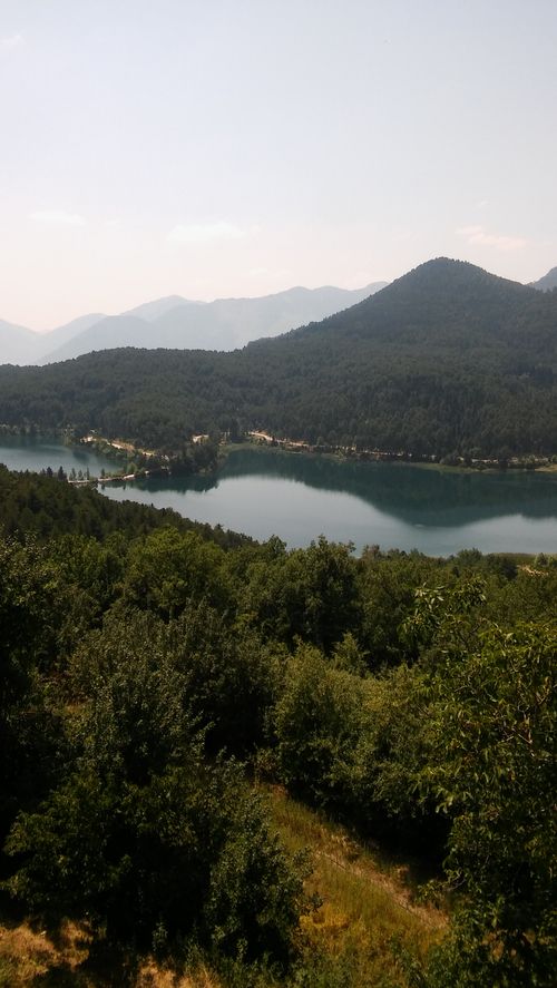Free Stunning aerial view of a serene lake surrounded by lush forest and hills in Πελοπόννησος, Ελλάδα. Stock Photo