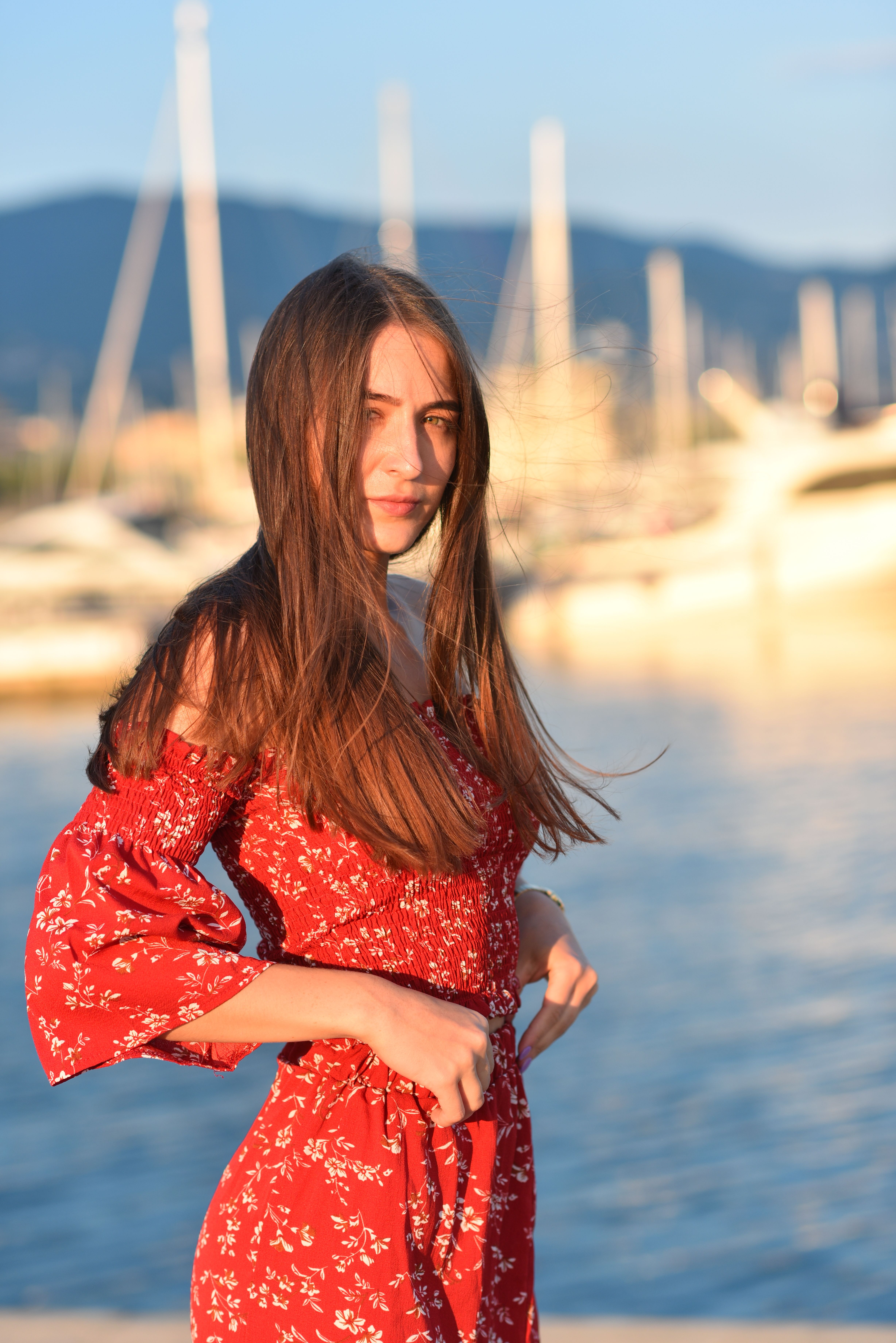 Elegant fashion portrait of a woman by the marina at sunset.