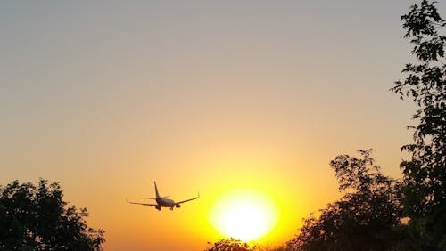 White Airplane in Mid Air during Yellow Sunset