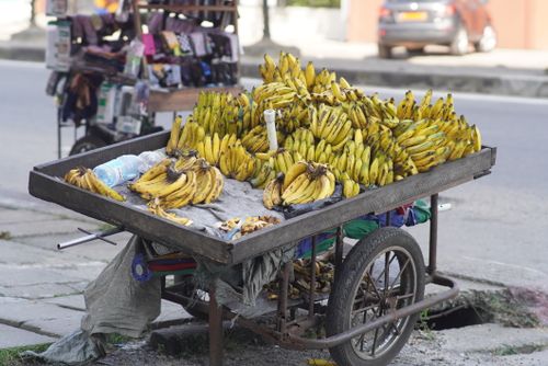 Free A street vendor's cart in Douala filled with ripe bananas, capturing urban street life in Cameroon. Stock Photo