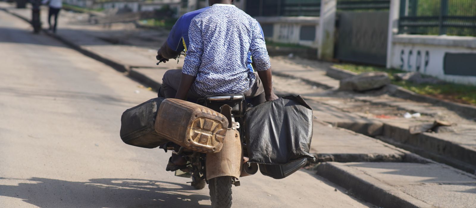 A man rides a motorbike with luggage on a sunny day in Douala, Cameroon. — flights from Yaounde to Douala