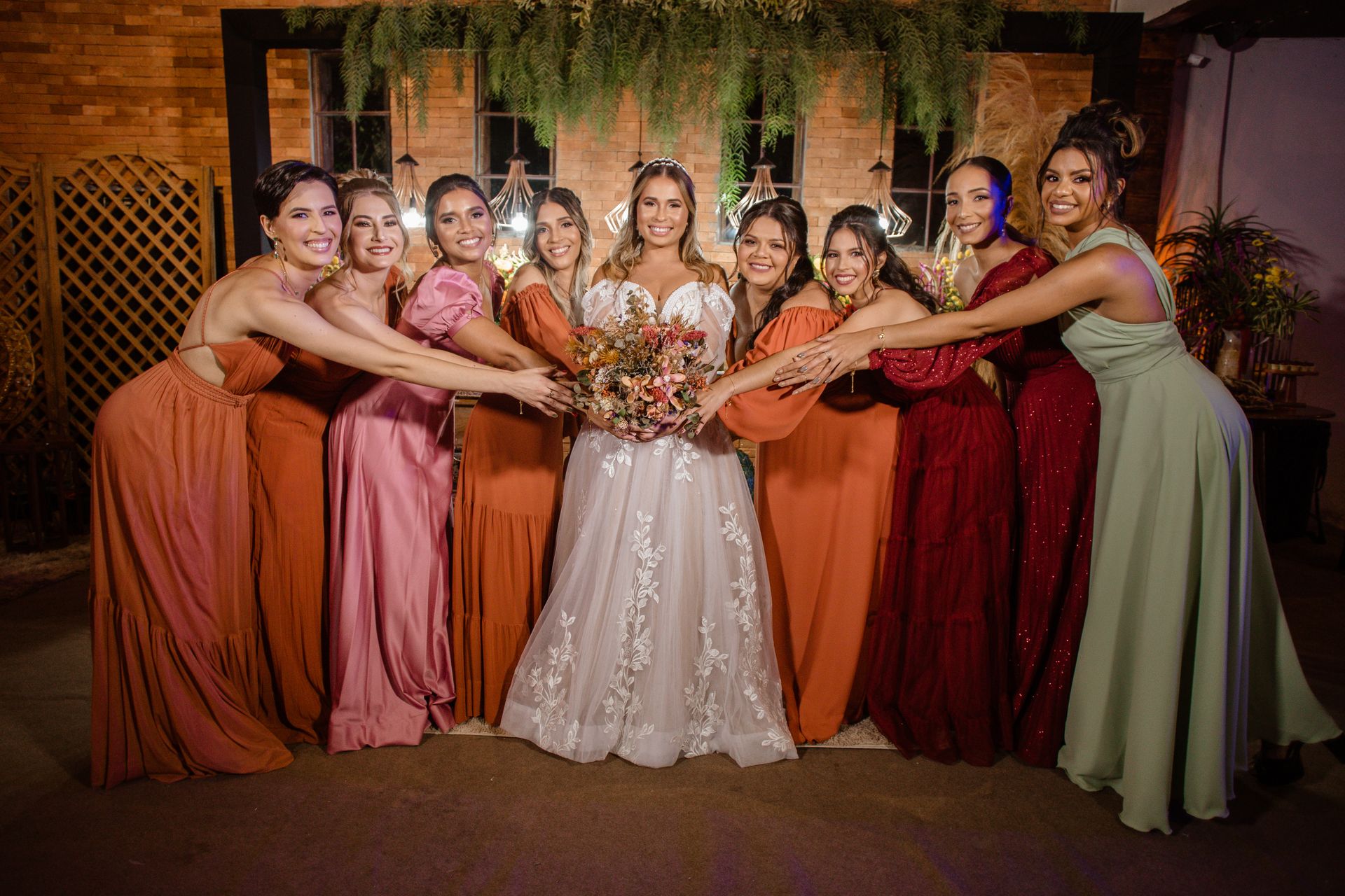 A cheerful bride and bridesmaids celebrate together with vibrant dresses indoors.