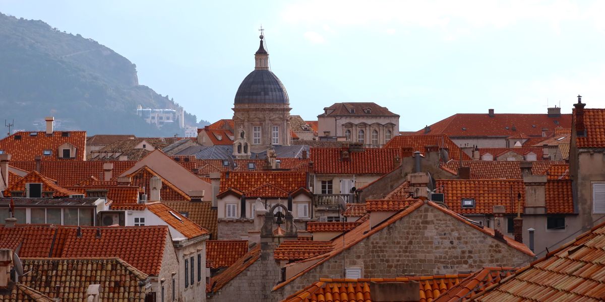 Os telhados de terracota da cidade velha de Dubrovnik com a cúpula da catedral e o Monte Srd ao fundo