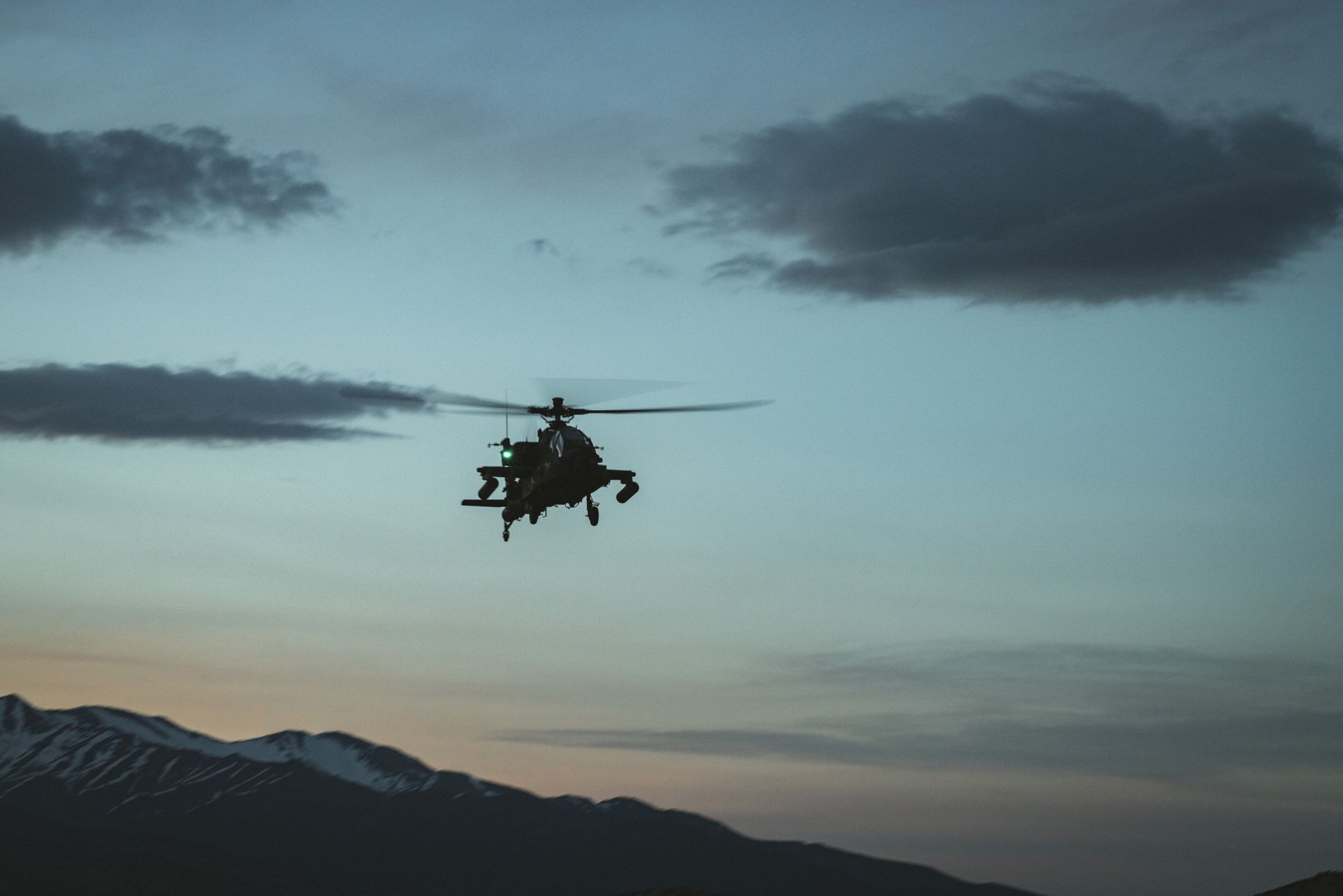 Alacakaranlık gökyüzünde bir askeri helikopterin silueti