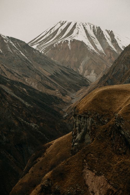 Free A breathtaking view of rugged, snowcapped mountains under overcast skies. Stock Photo
