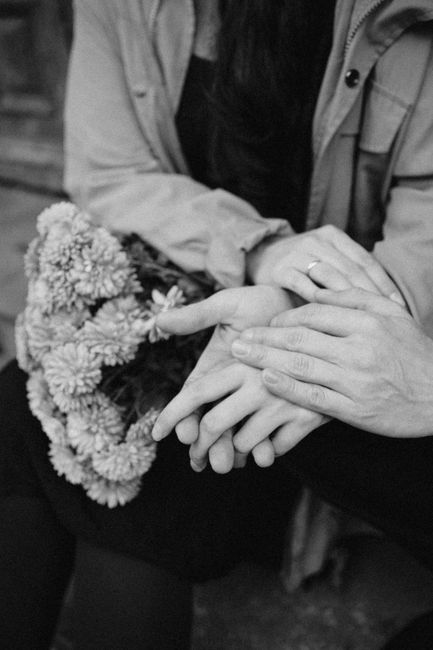 Close-up of a couple's hands with engagement ring and flowers, showcasing love.