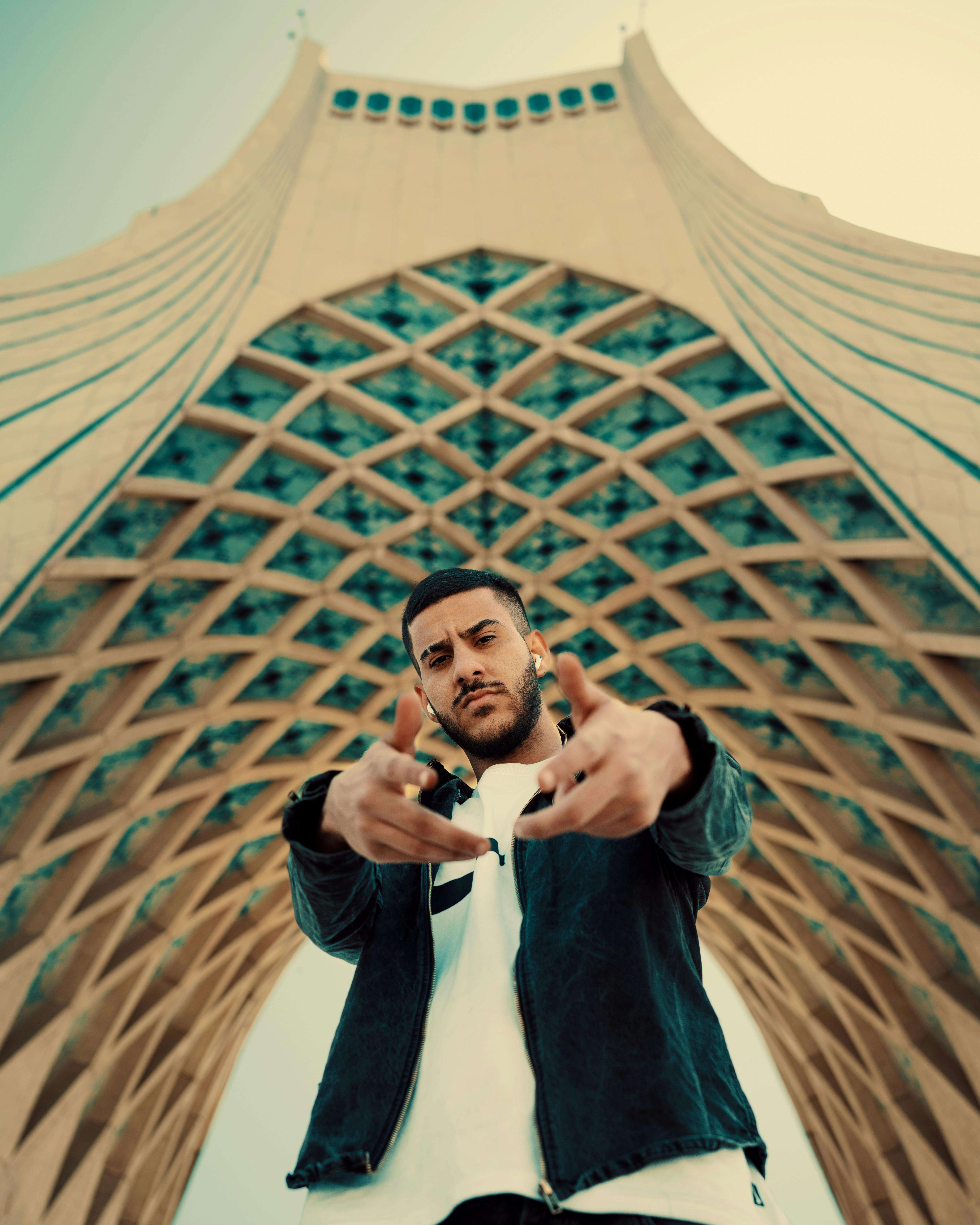 young man posing under the archway of the azadi tower in tehran iran