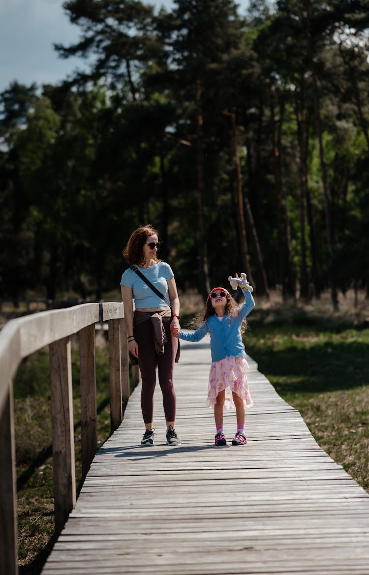 Mother With Daughter On Wooden Footpath In Forest