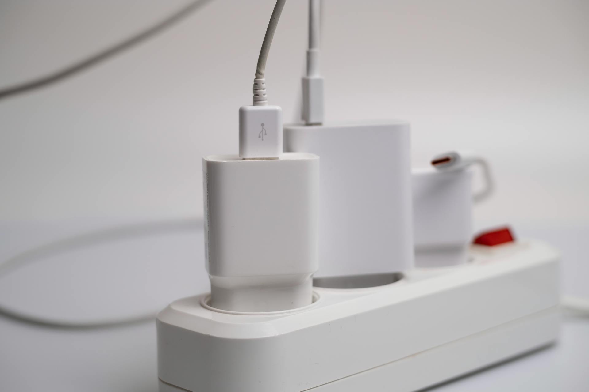 Many chargers are connected to an electrical outlet on a white background.